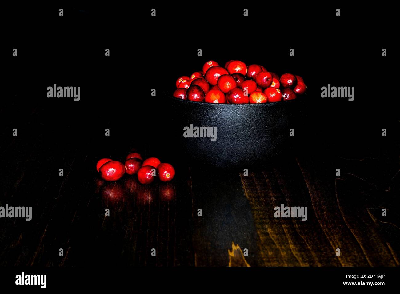 A bunch of cranberries in a black, cast iron bowl, with black