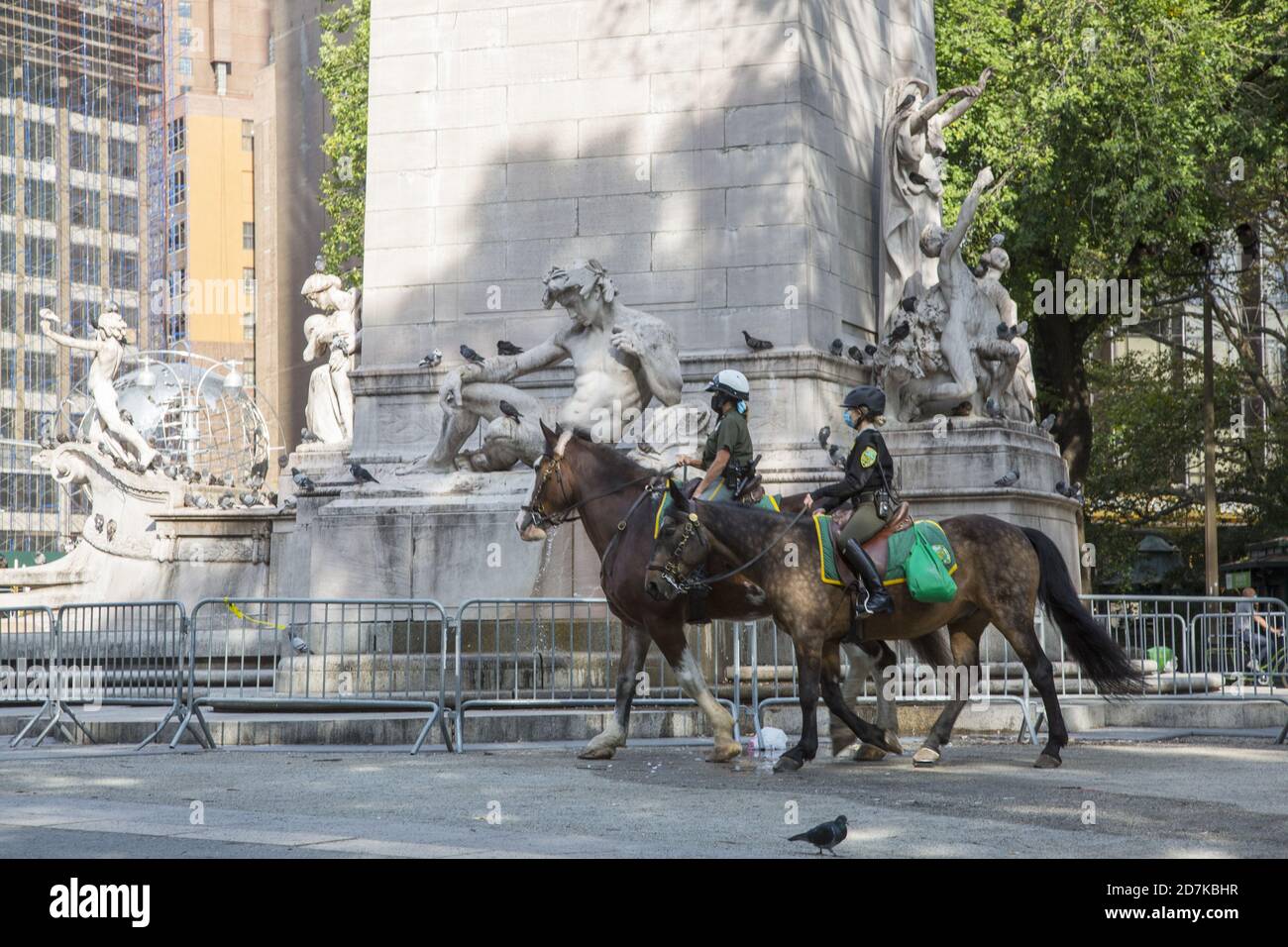 Park rangers on horseback ride passed the USS Maine National Monument at the Columbus Circle entrance to Central Park in NYC. Stock Photo