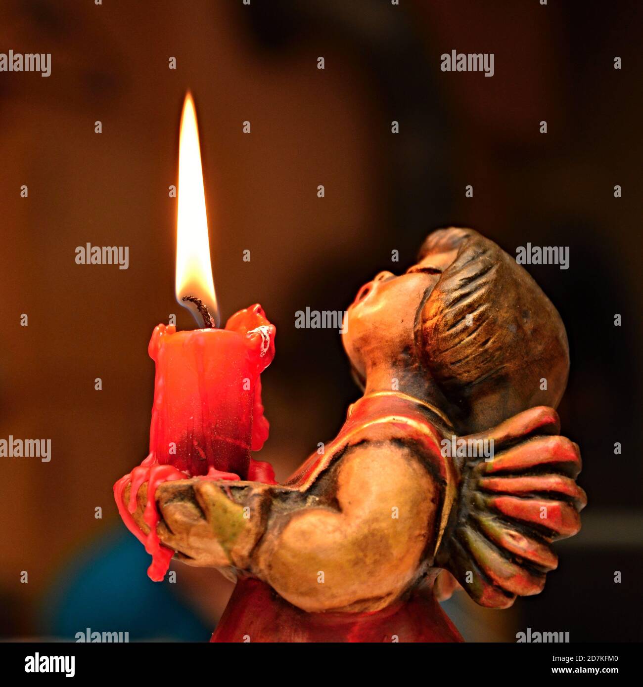 Wooden angel with a burning candle in his arms. Christmas mood, peace and relaxation. Stock Photo