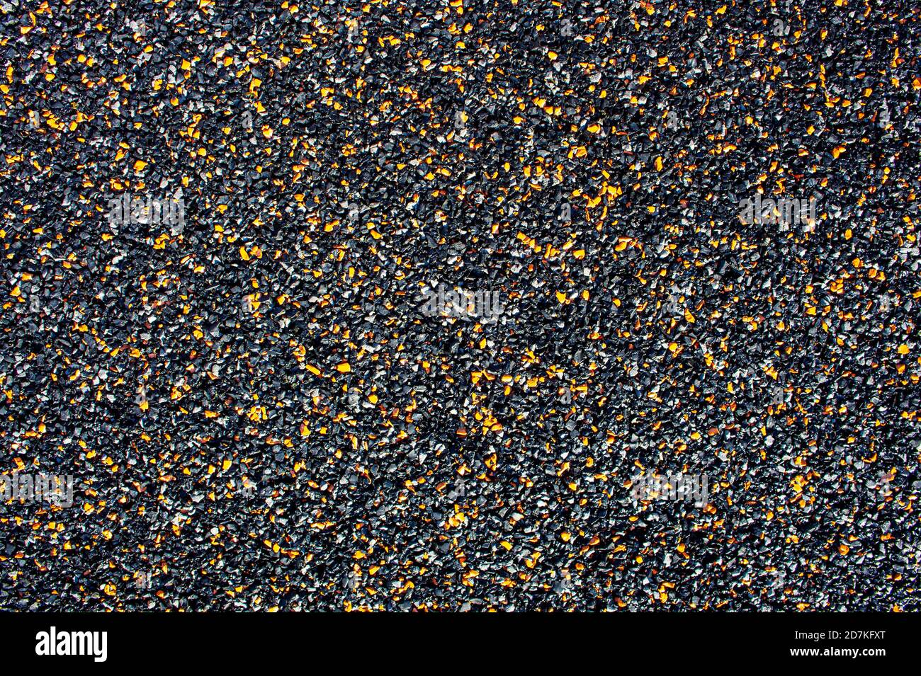 Dark abstract background from small stone chips of black and orange colors. Copy space. Ground coverage Stock Photo