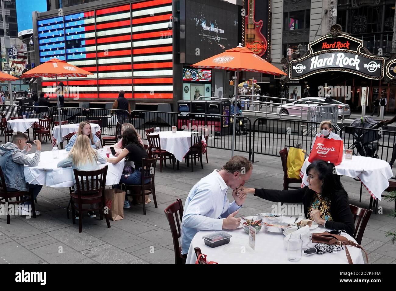 A man kisses a woman's hand after saying grace before dining outside at a pop up restaurant set up in Times for 'Taste of Times Square Week' during the coronavirus disease (