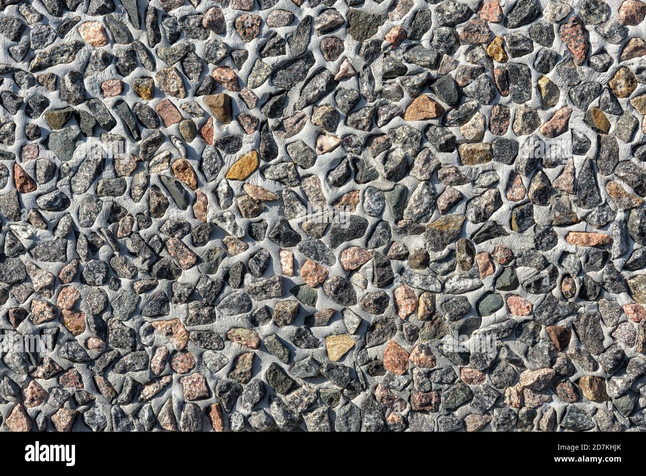 Wall decorated lot of small stones, abstract texture background. Many granite stones in cement or concrete surface, pattern on modern building exterio Stock Photo
