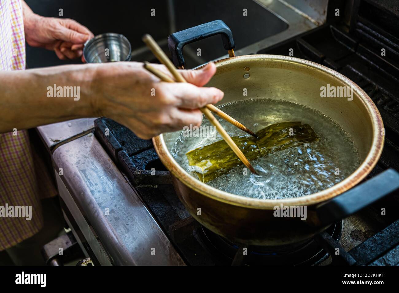 Making a Japanese miso soup in Nishiizu, Japan. The first step on the way to a miso soup bursting with umami is to add kombualge to boiled water Stock Photo