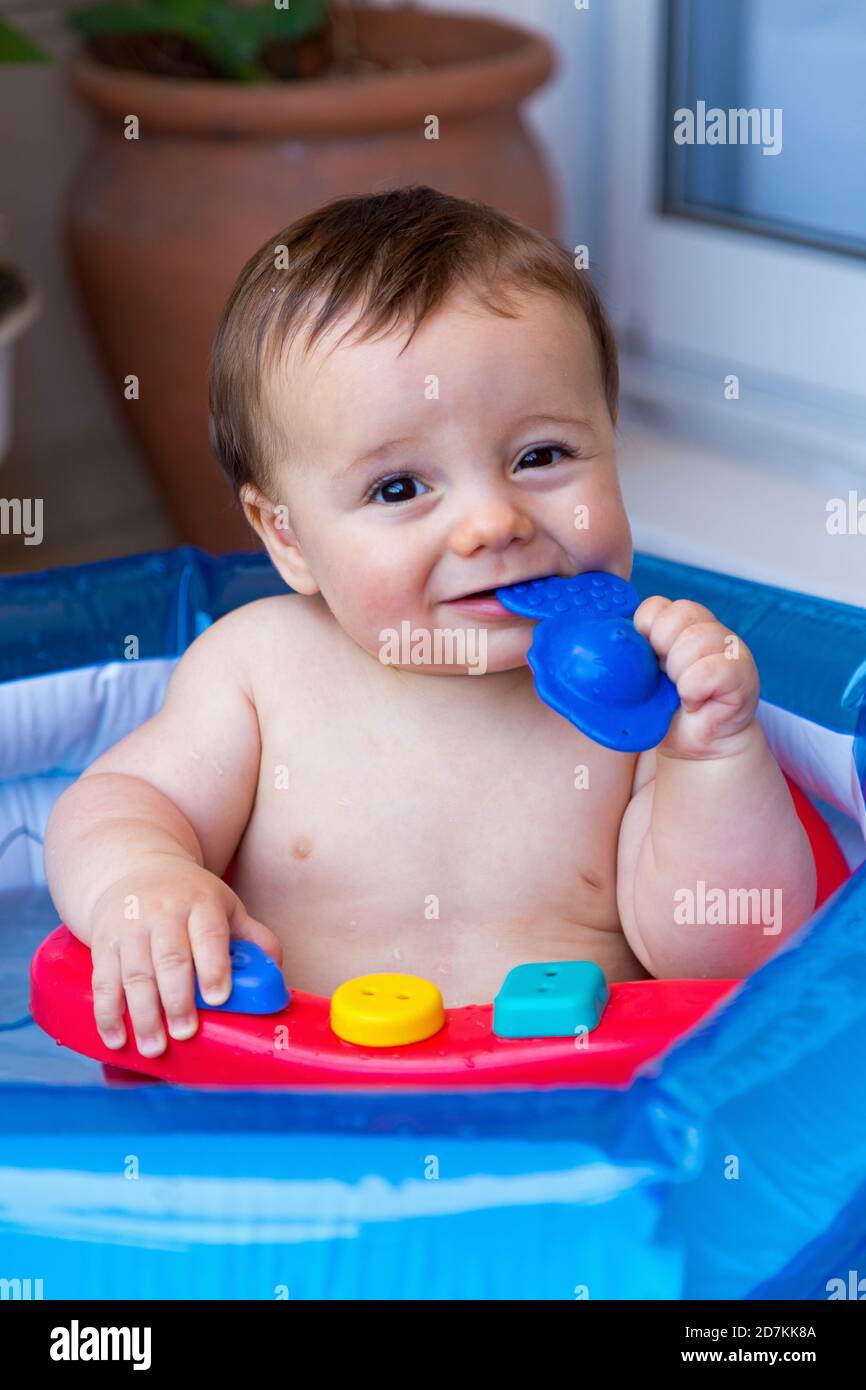 Baby taking a bath and playing in a little inflatable pool. Toddler