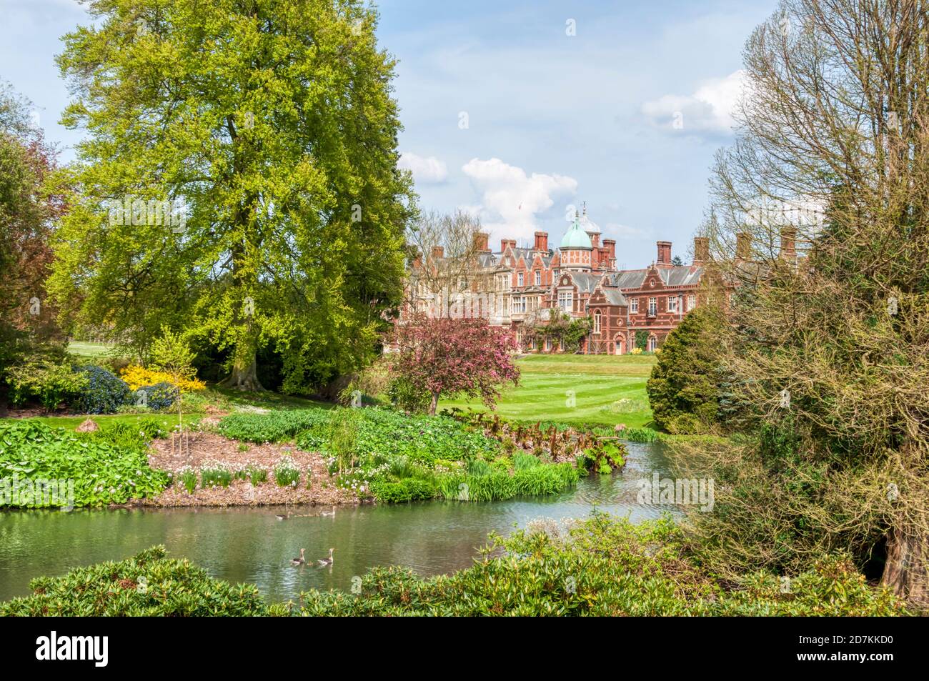 Sandringham House seen across the ornamental gardens and part of the lake in the grounds. Stock Photo