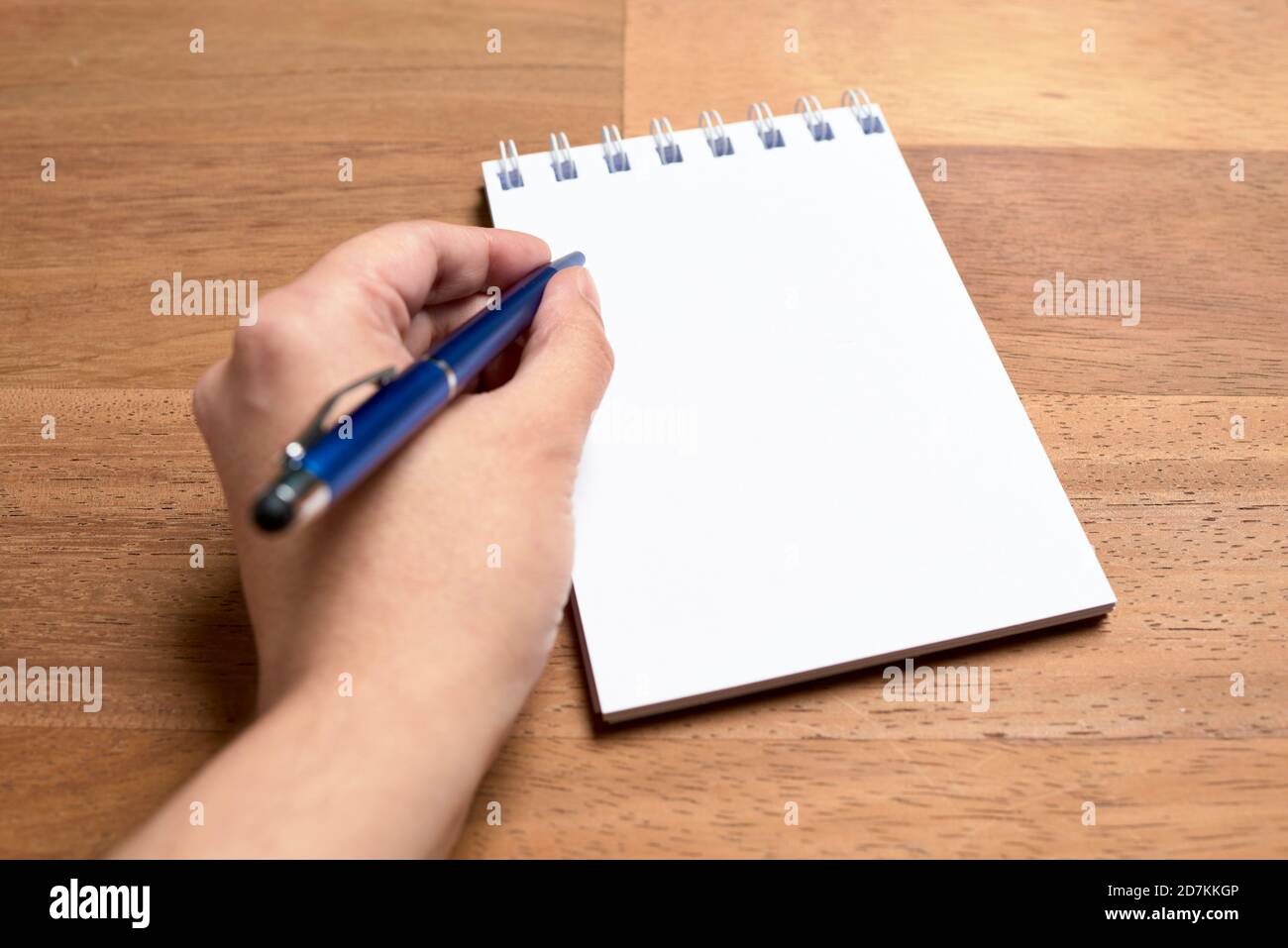 Left hand of a young lefthanded caucasian woman writing with a blue