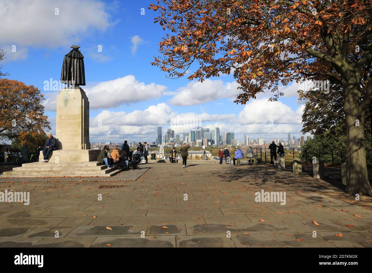 Next to the statue of General James Wolfe, people look the at view from the top of Greenwich Park, towards Canary Wharf, in Autumn, SE London, UK Stock Photo