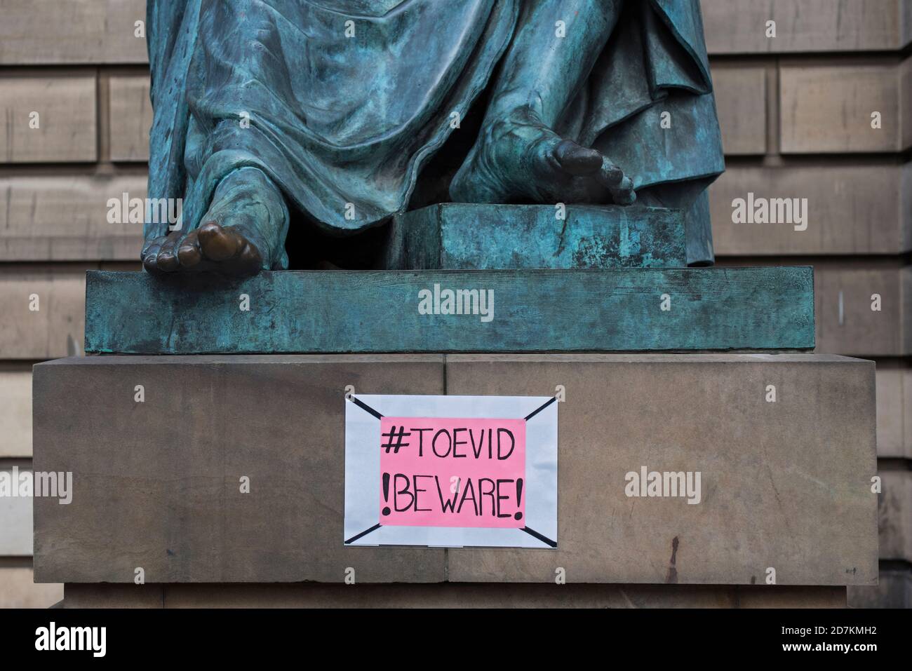 #Toevid !Beware! sign on the statue of the philosopher and historian David Hume by sculptor Sandy Stoddart on Edinburgh's Royal Mile. Stock Photo