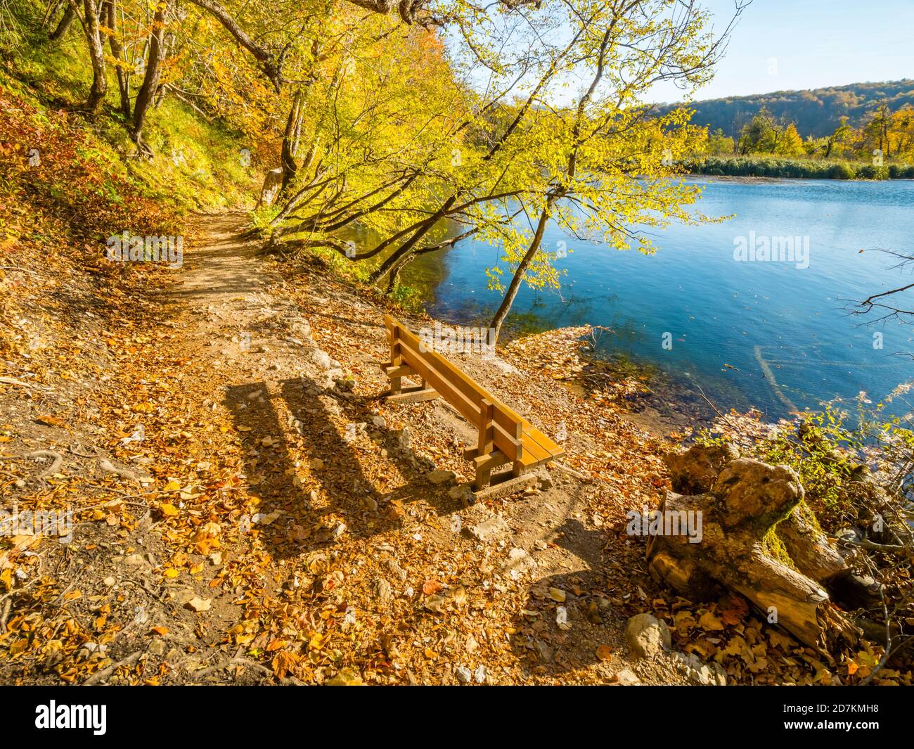 Plitvice lakes in Croatia Europe wooden park bench in morning spectacular Autumnal Autumn colors trail pathway calm lake Stock Photo