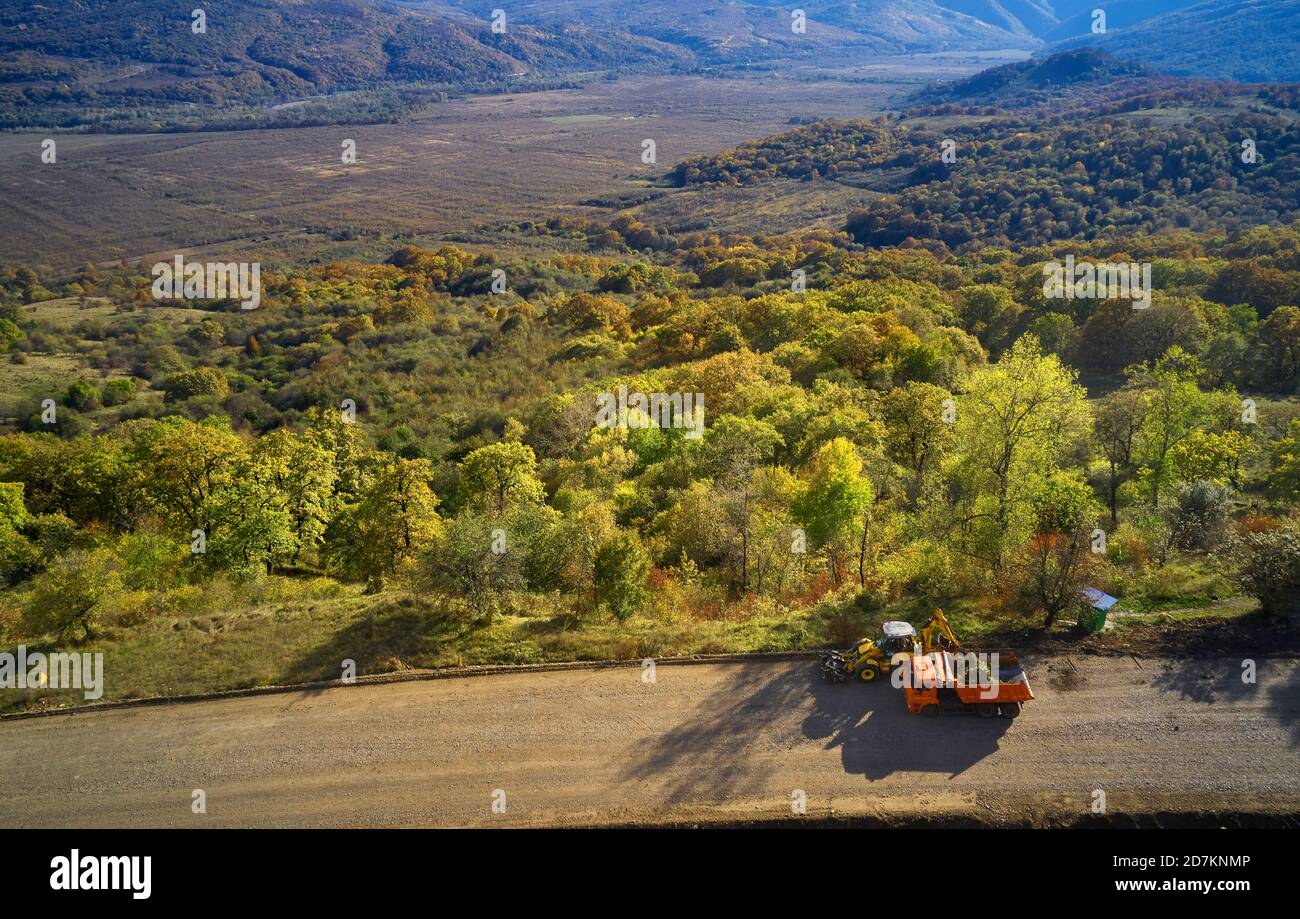 Almaty, Kazakhstan - May 13, 2019 - Road workers are painting white line on mountain road. Road cones with red and yellow stripes in background, stand Stock Photo