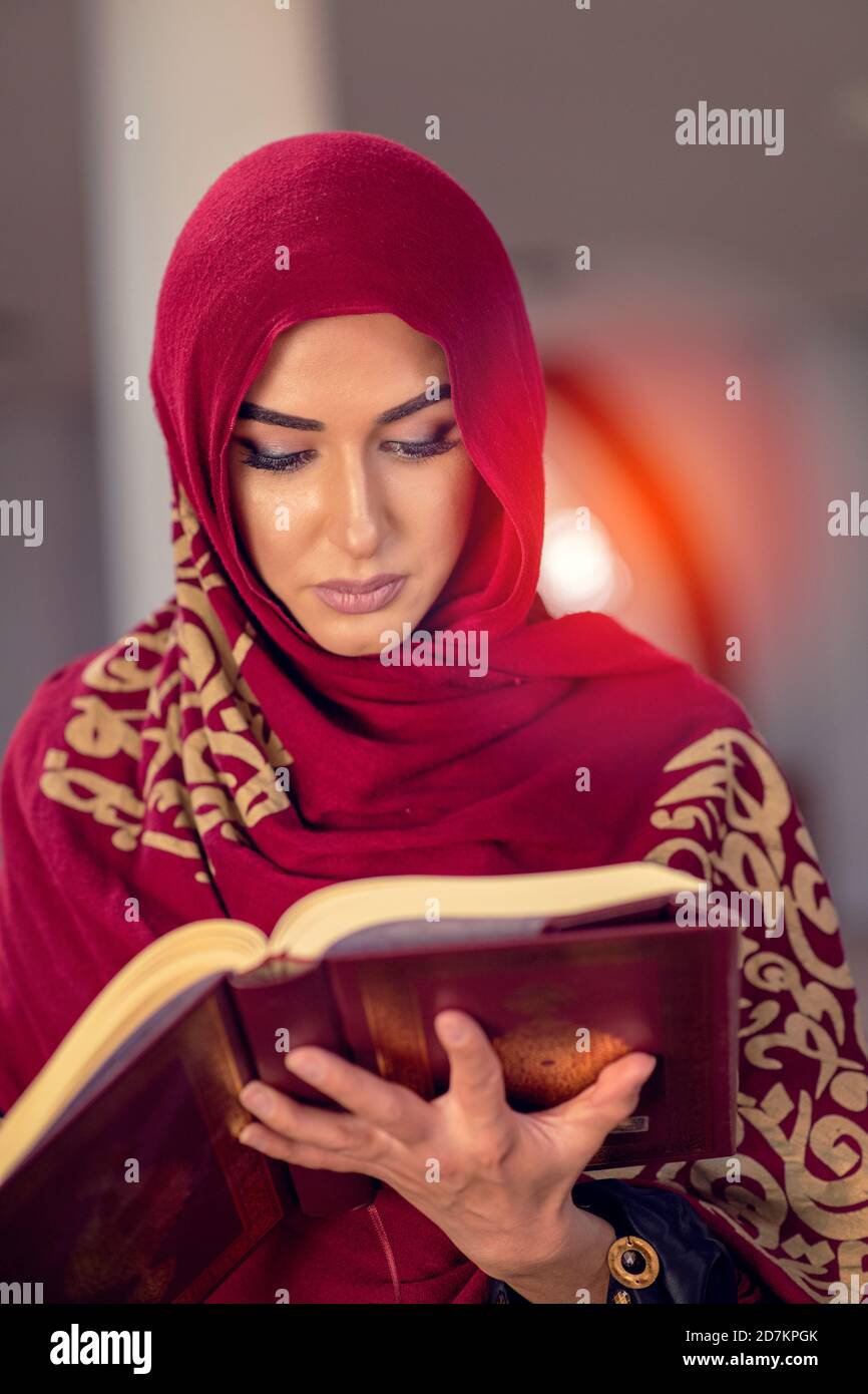 Young muslim woman reading Quran in the mosque and sunlight falling from the window Stock Photo