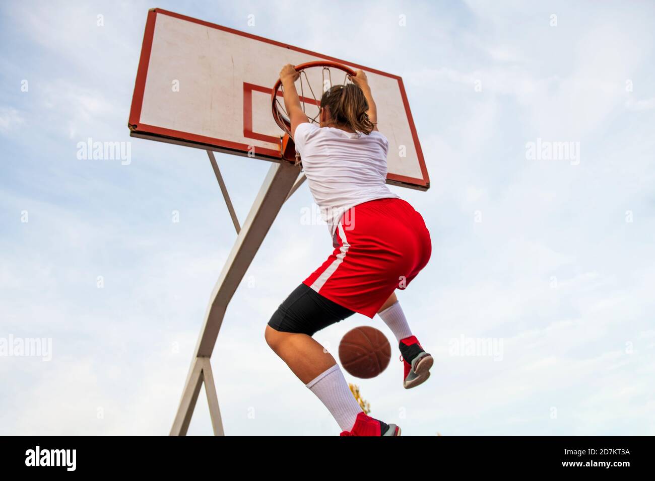 Females playing basketball on street court. Woman streetball player making slam dunk in a basketball game. Stock Photo