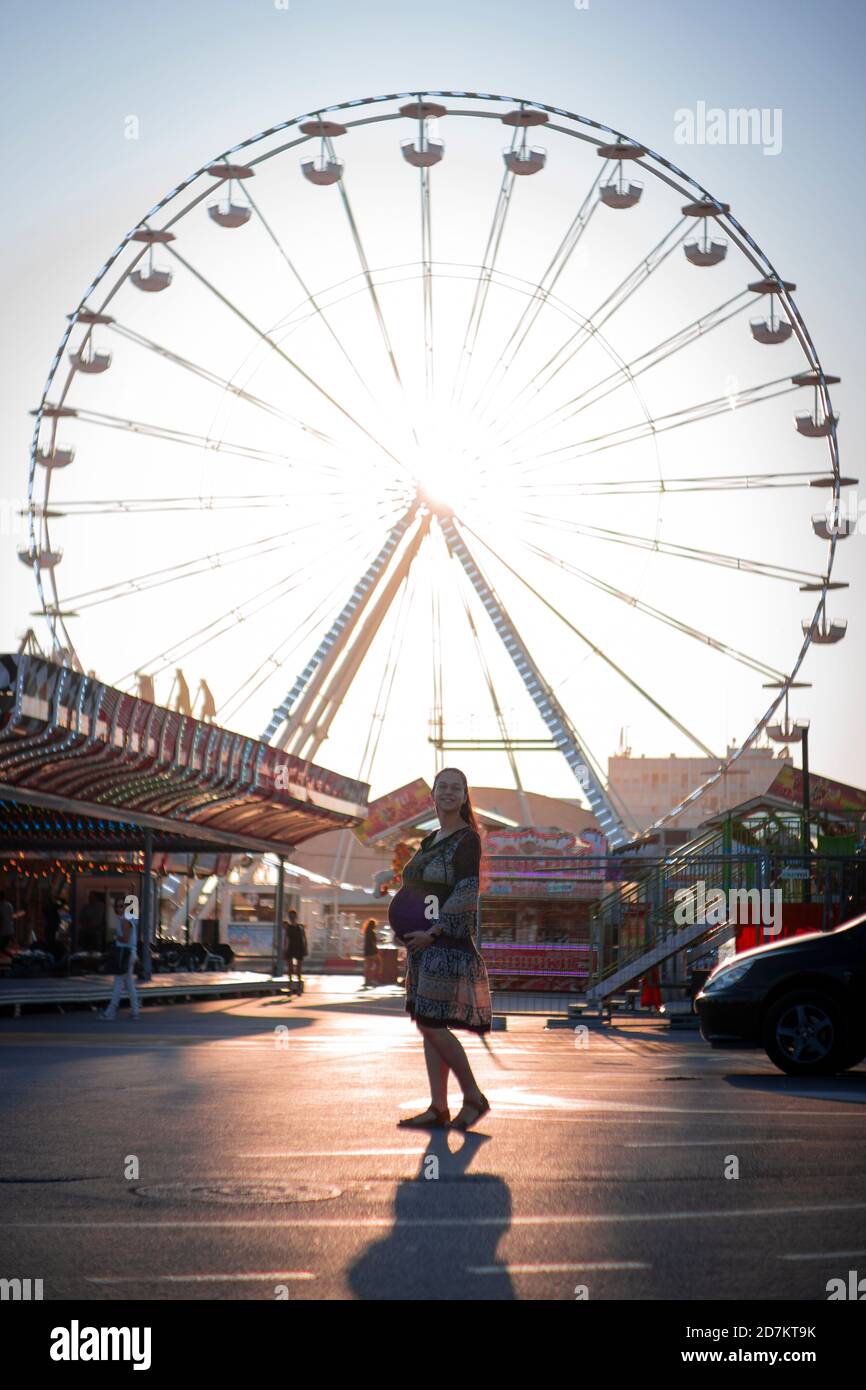 Pregnant Woman Enjoying Ferris Wheel At An Amusement Park With Sunset