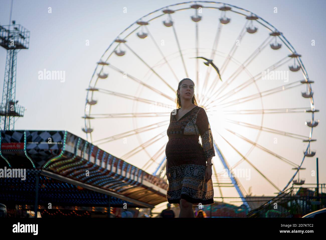 Pregnant Woman Enjoying Ferris Wheel At An Amusement Park With Sunset
