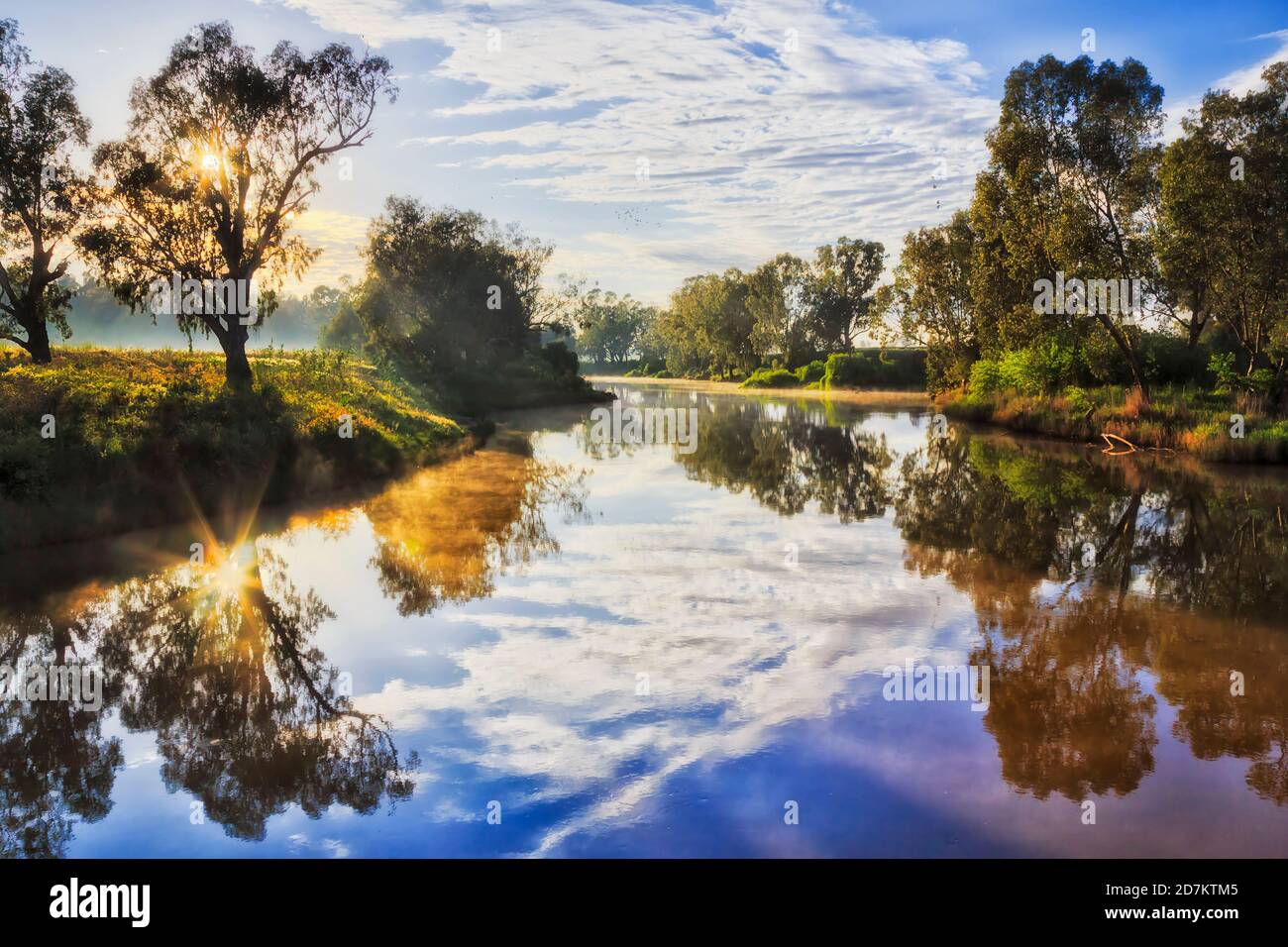 Reflection of the sun in calm still waters of Macquarie river at sunrise in Dubbo city of Australia. Stock Photo