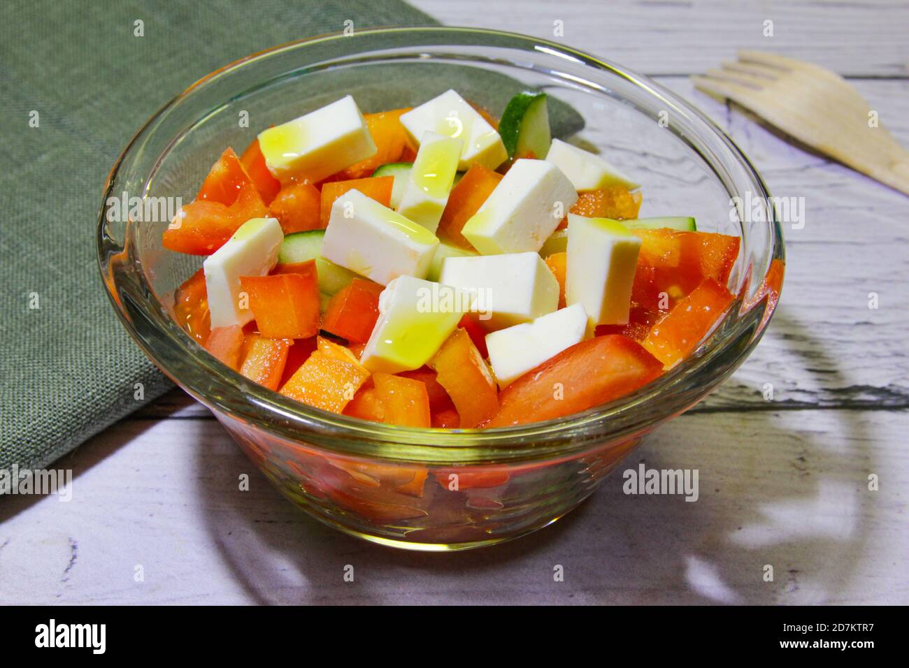 Salad with vegetable cucumber, tomatoes and cheese in transparent bowl Stock Photo