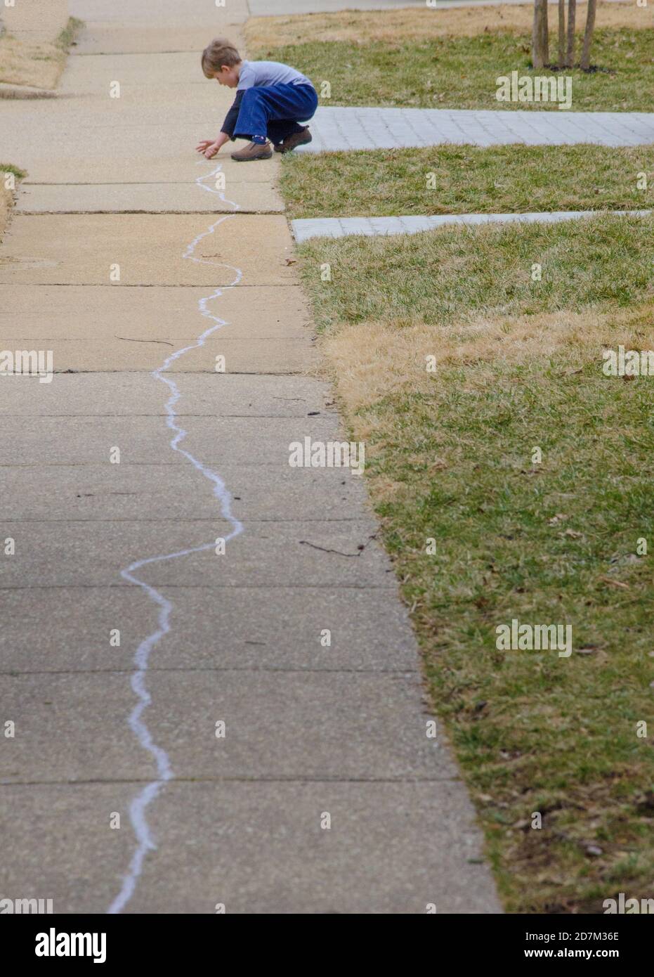 A young boy draws with chalk on the sidewalk. Photo by Liz Roll Stock ...