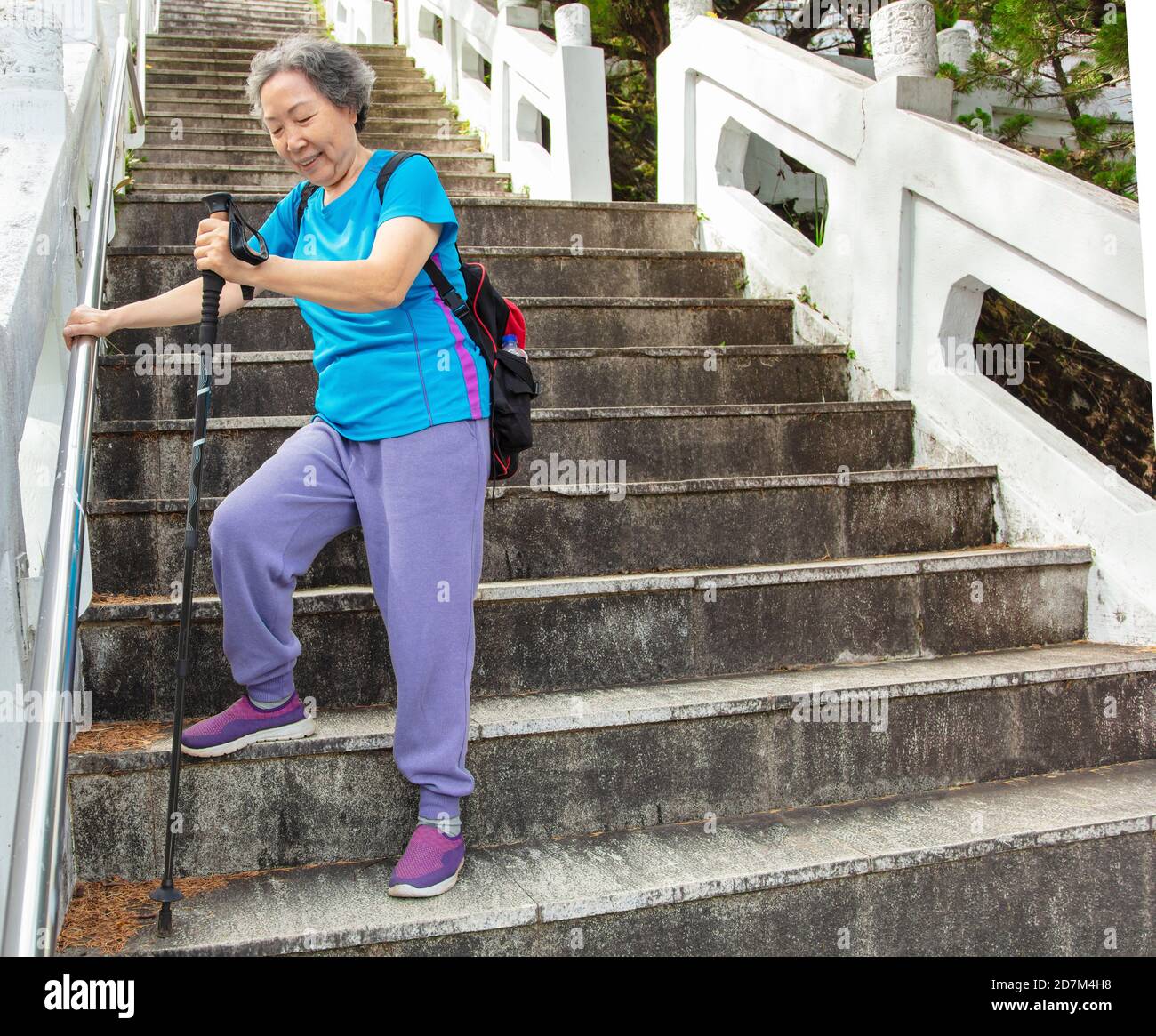 Asian senior woman goes downstairs Stock Photo