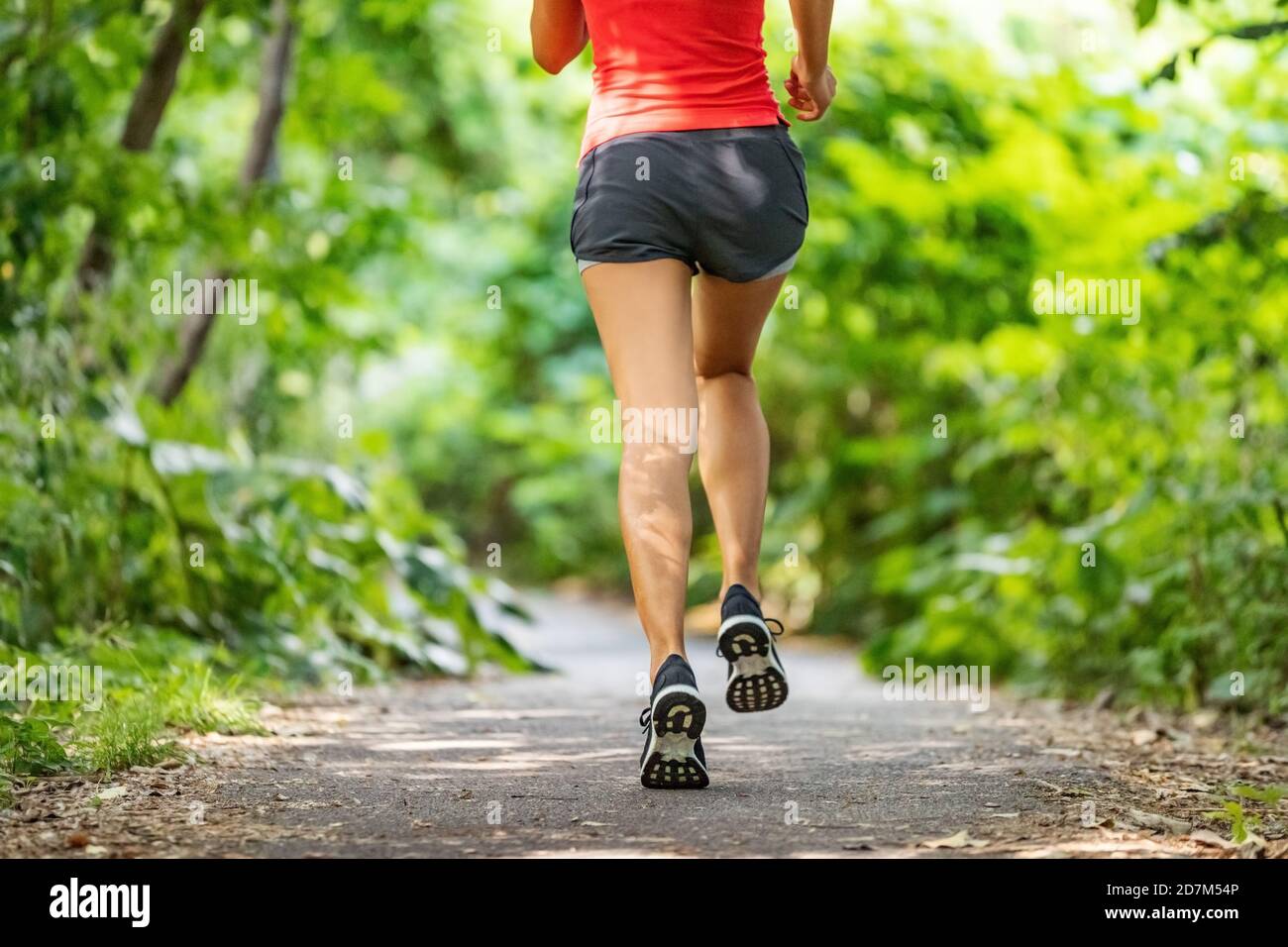 Runner running legs from the back jogging on nature path outside. Running shoes girl training cardio outdoors Stock Photo
