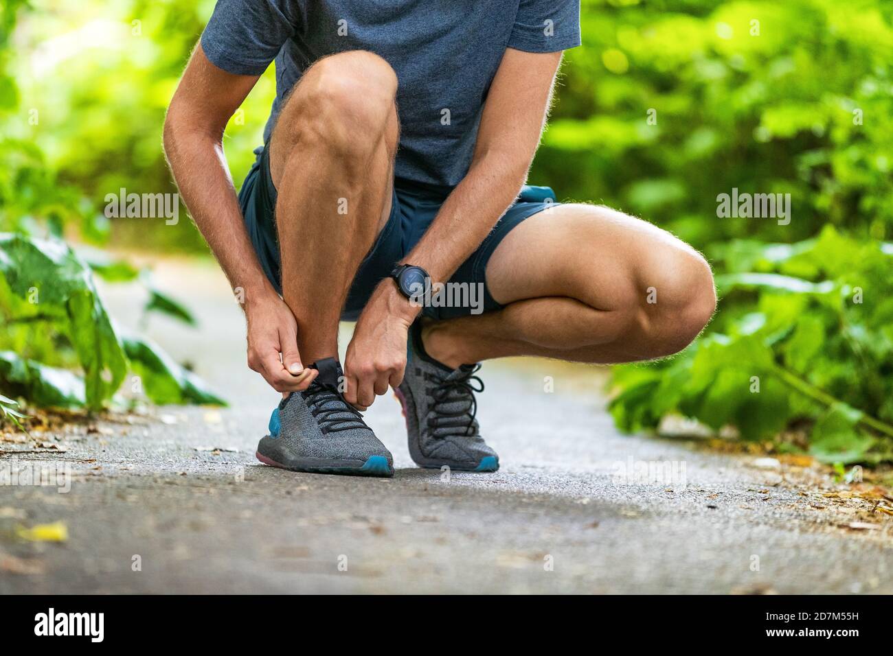 Running shoes sports smartwatch man tying shoe laces. Male fitness runner getting ready to jog in spring autumn jogging outdoor wearing technology Stock Photo