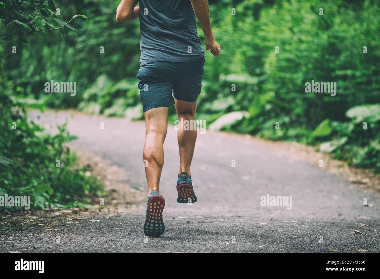 Runner man athlete jogging in city run on park path running view from back summer outdoor green forest Stock Photo