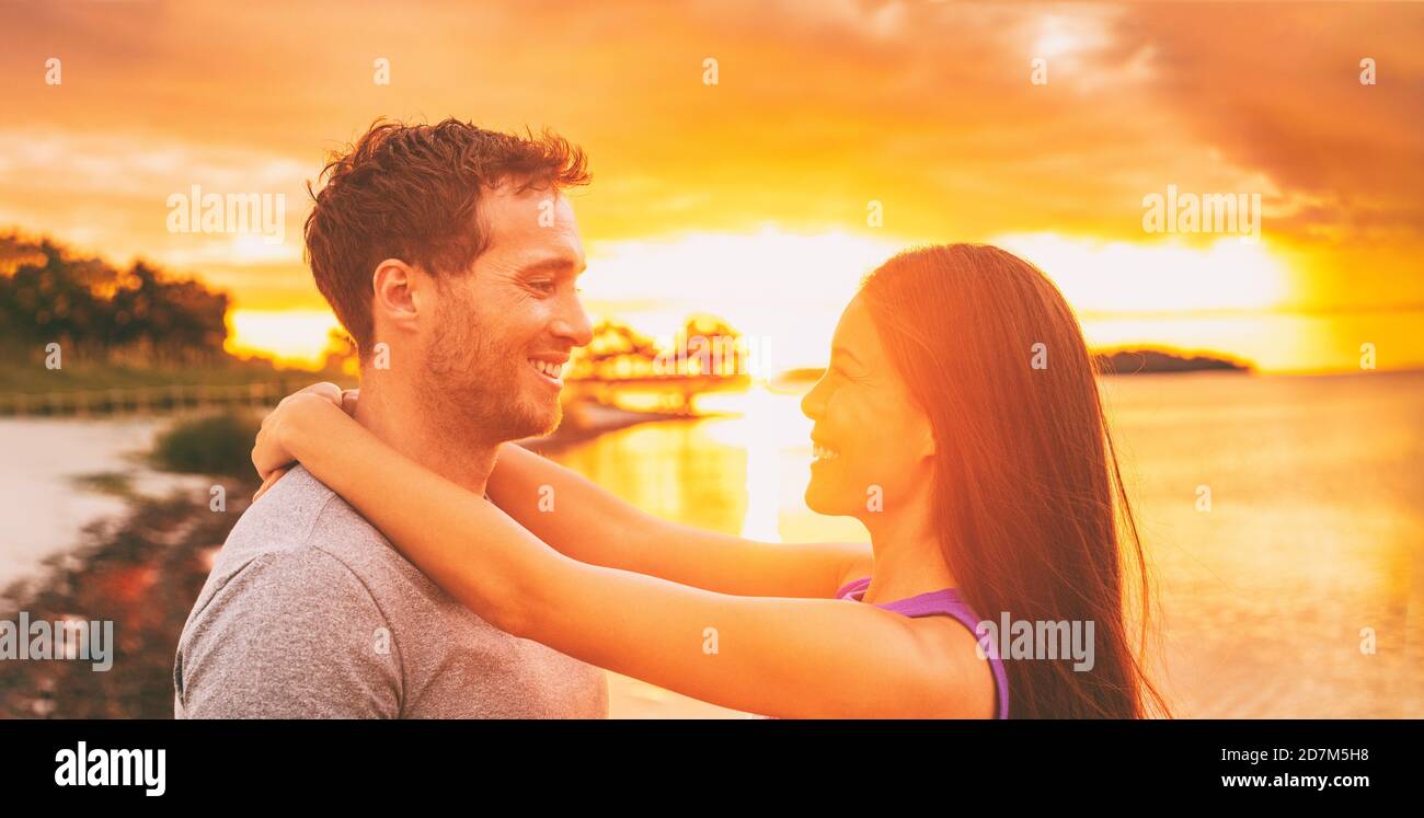 Happy couple in love embracing at sunset glow on Florida beach summer  vacation background. Asian woman with arms around neck of caucasian  boyfriend Stock Photo - Alamy