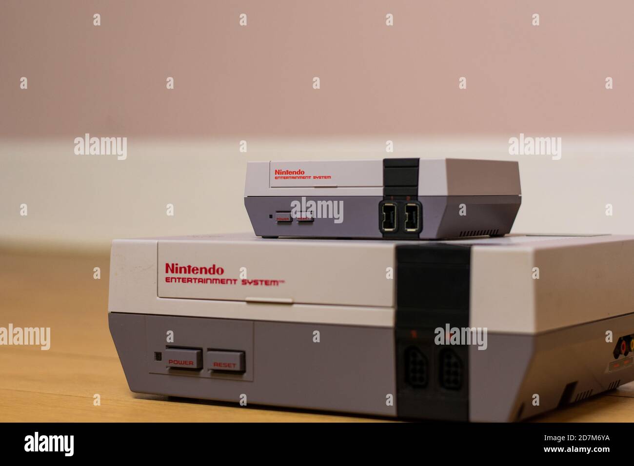A Nintendo Entertainment System Classic Edition on Top of an Original Nintendo Entertainment System, on a wood floor. Comparison of the original NES a Stock Photo