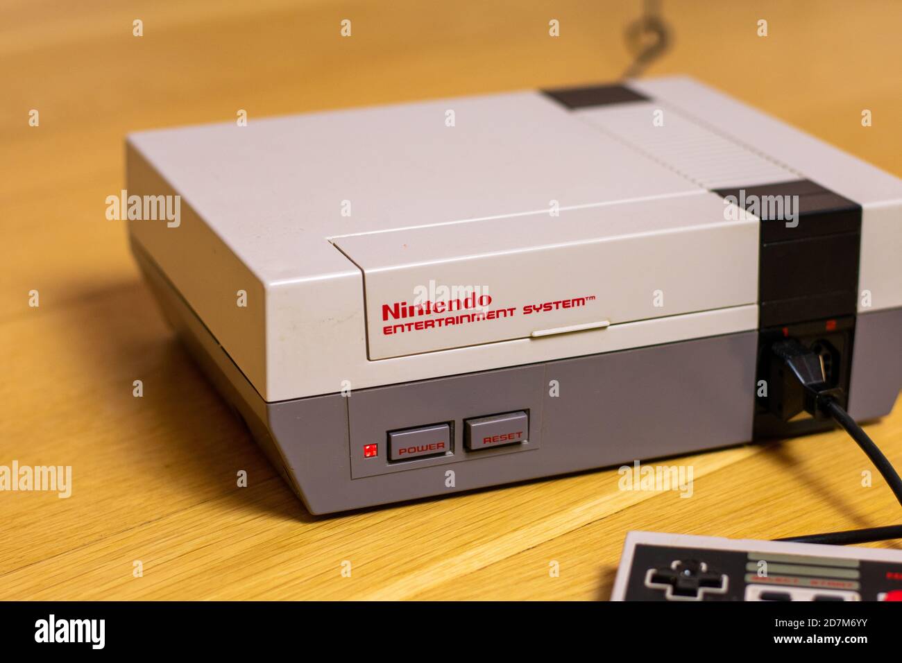 A Nintendo Entertainment System With a Controller Plugged In. The NES is a popular retro console. Stock Photo