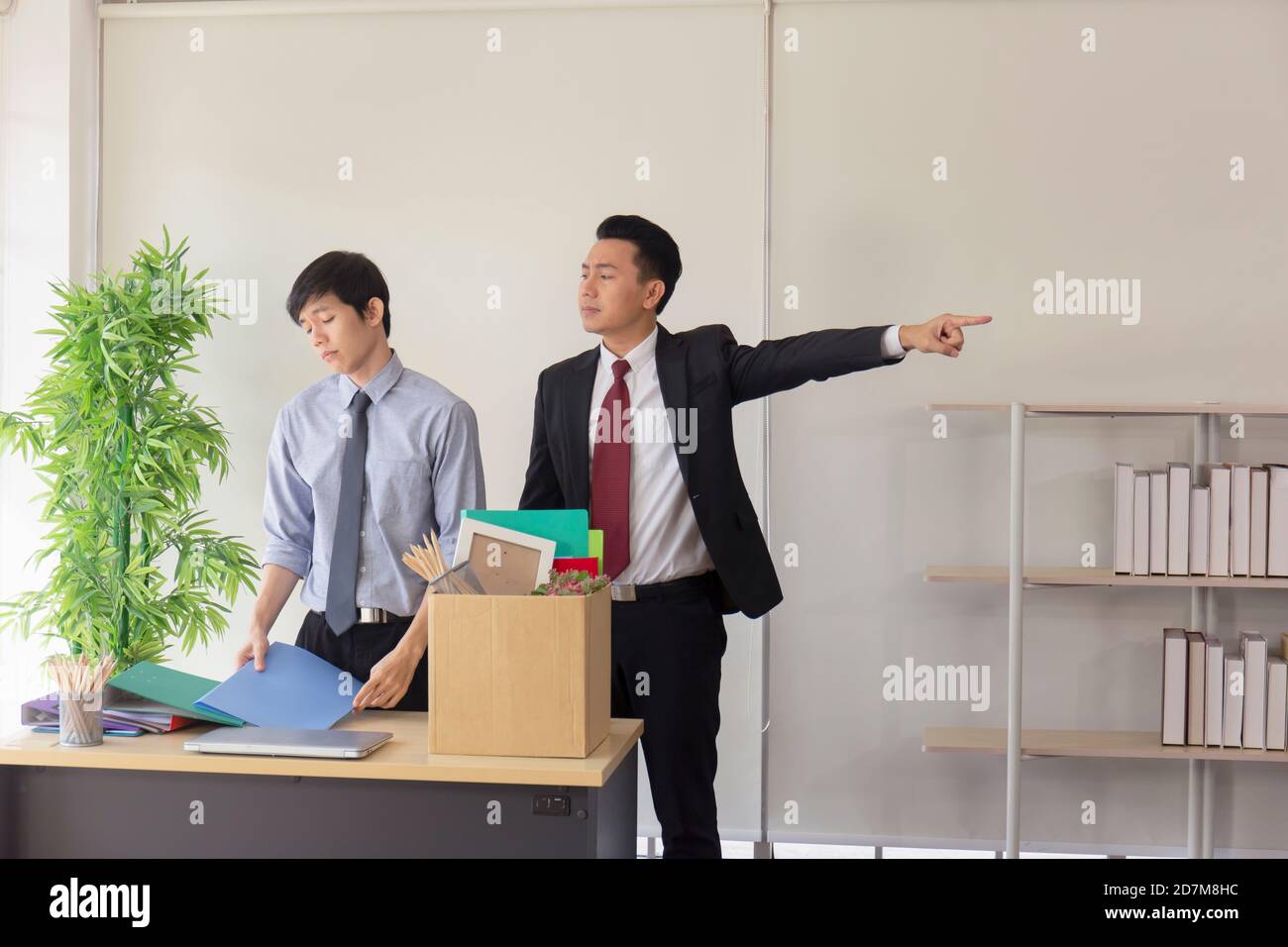 An Asian employee was fired from his job and was packing his personal ...