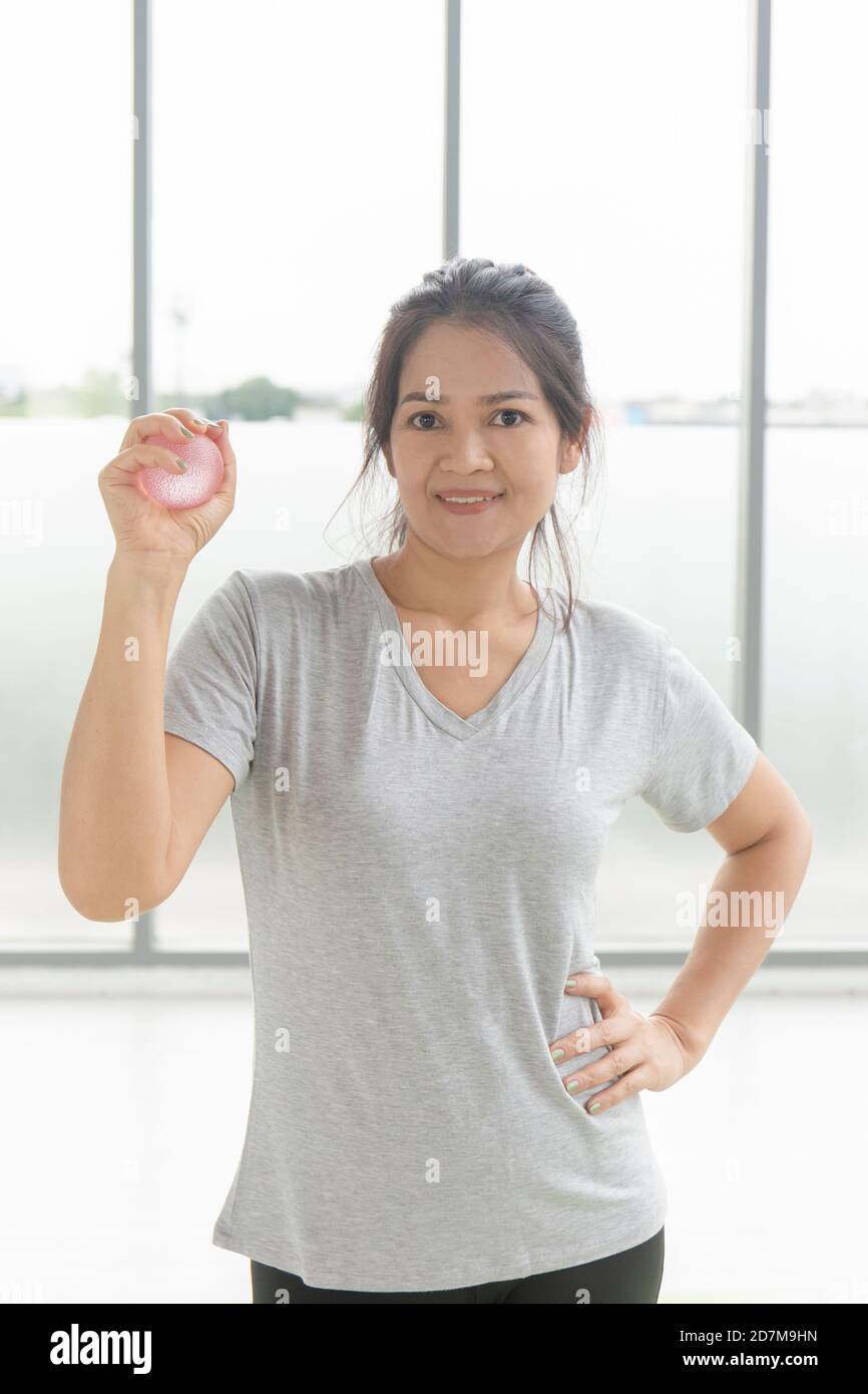 Asian woman closeup playing exercise equipment, rubber ball, hand