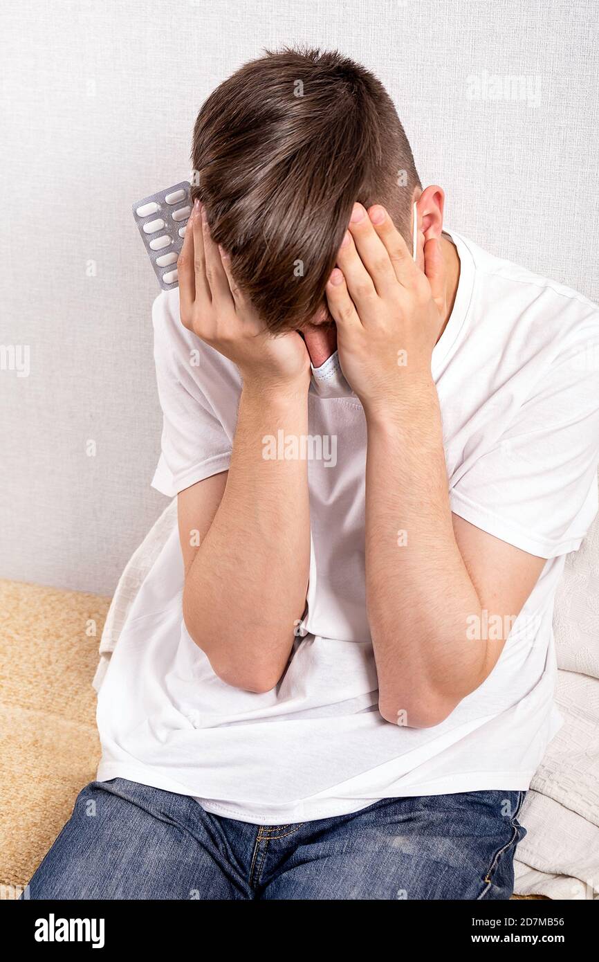 Young Man with a Pills feels Side Effect by the Wall at the Home Stock Photo