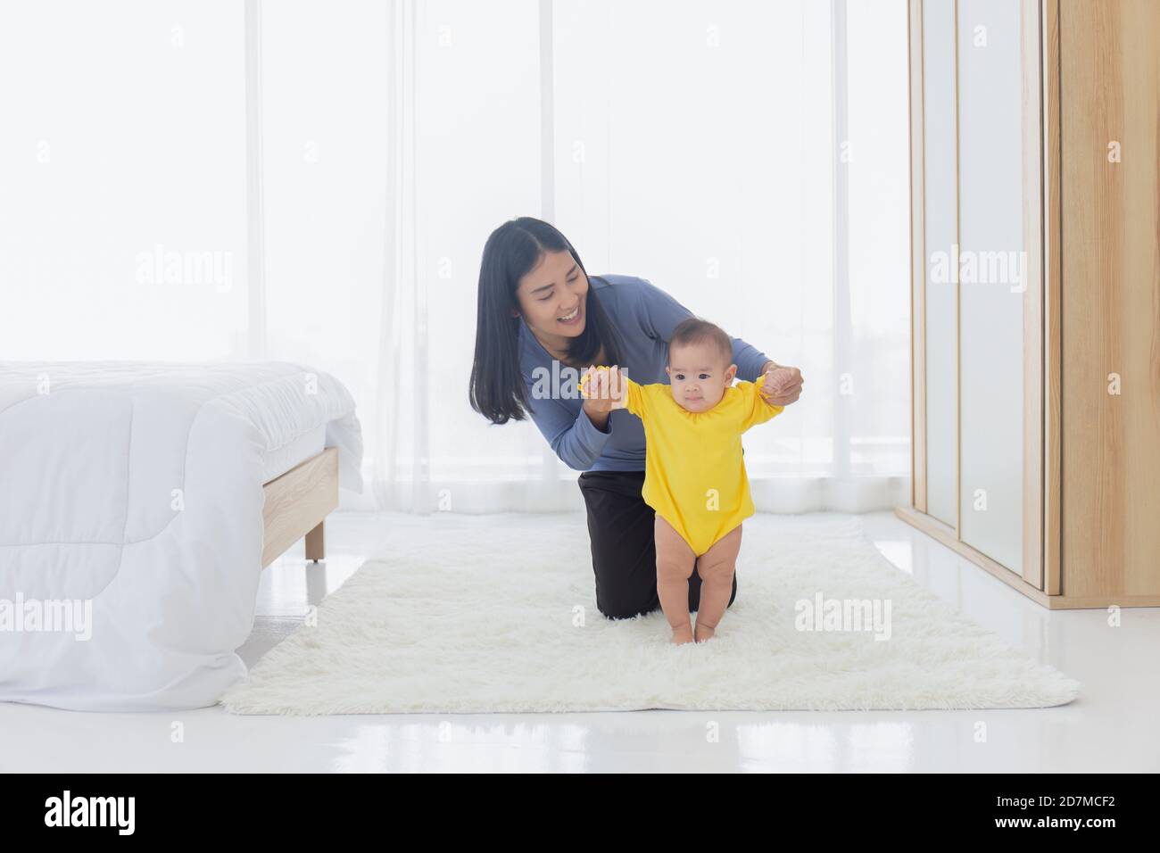 Mother helping baby daughter walk hi-res stock photography and images ...