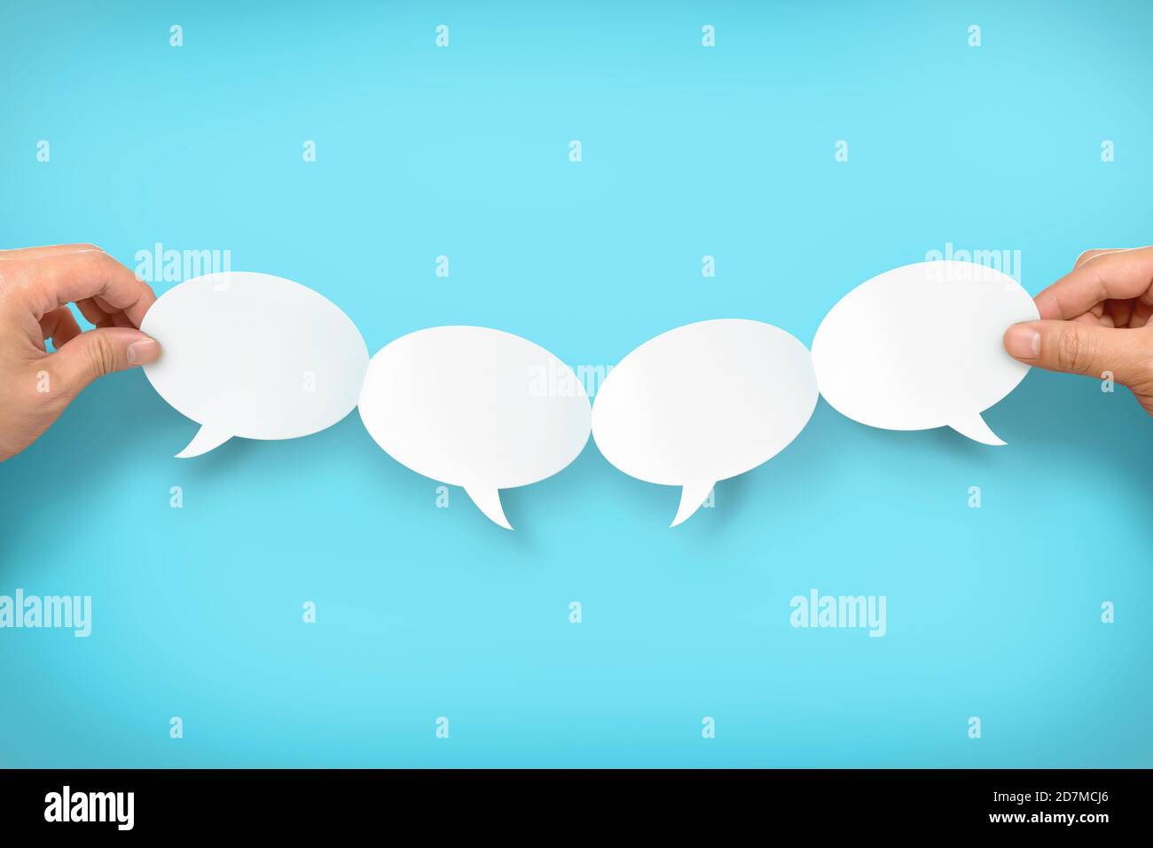 Two hands holding up four speech bubbles Stock Photo