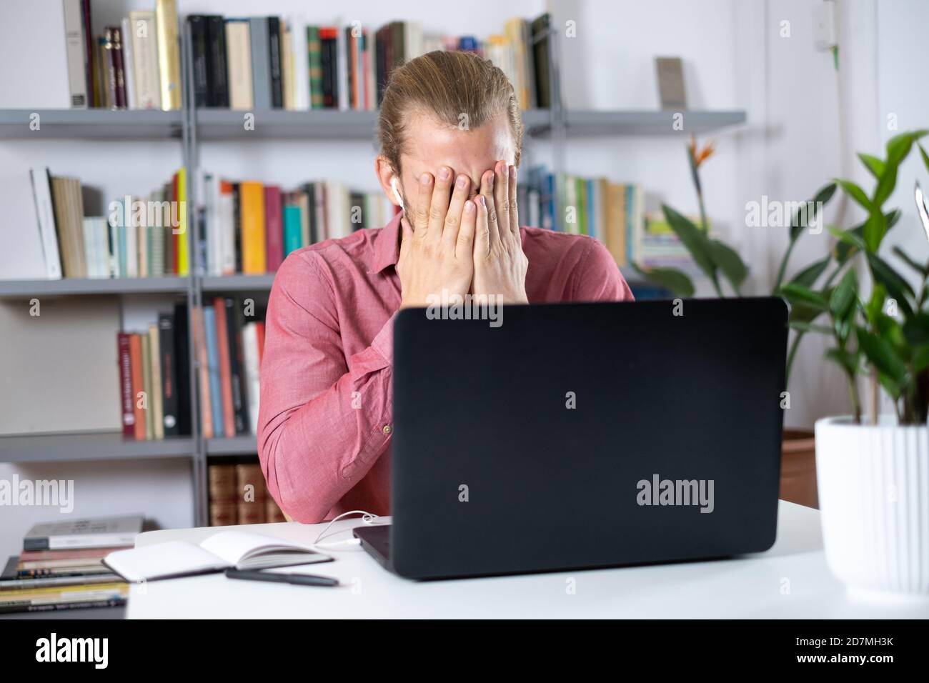 Attractive young man sitting at the table at home working with a laptop feeling worried and frustrated Stock Photo