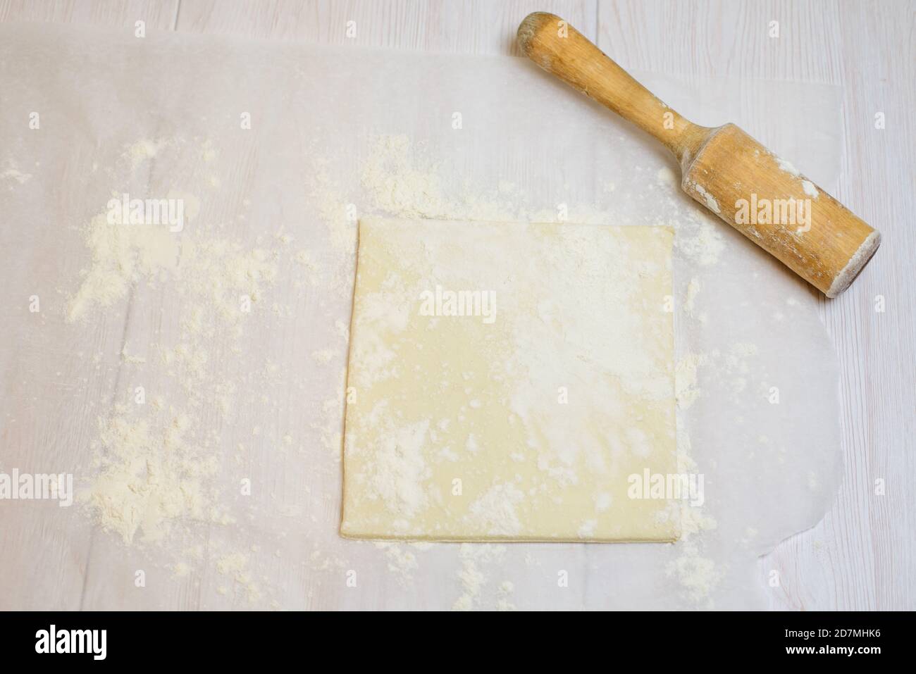 puff pastry and flour on parchment with flour and rolling pin . ingredients for cake Stock Photo