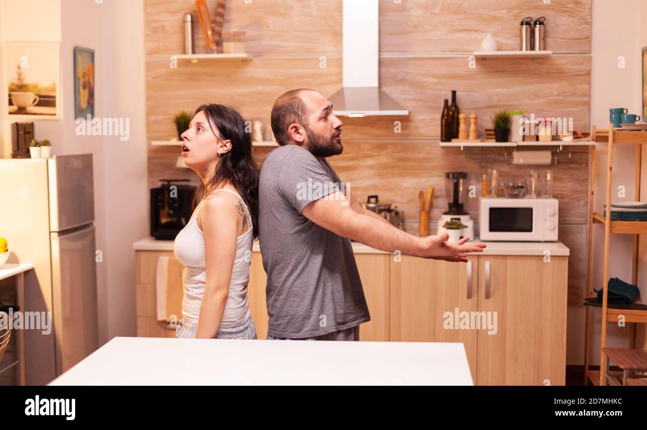 Husband annoyed by cheating wife staying back to back having a disagreement. Frustrated offended irritated accusing woman of infidelity arguing her. Stock Photo
