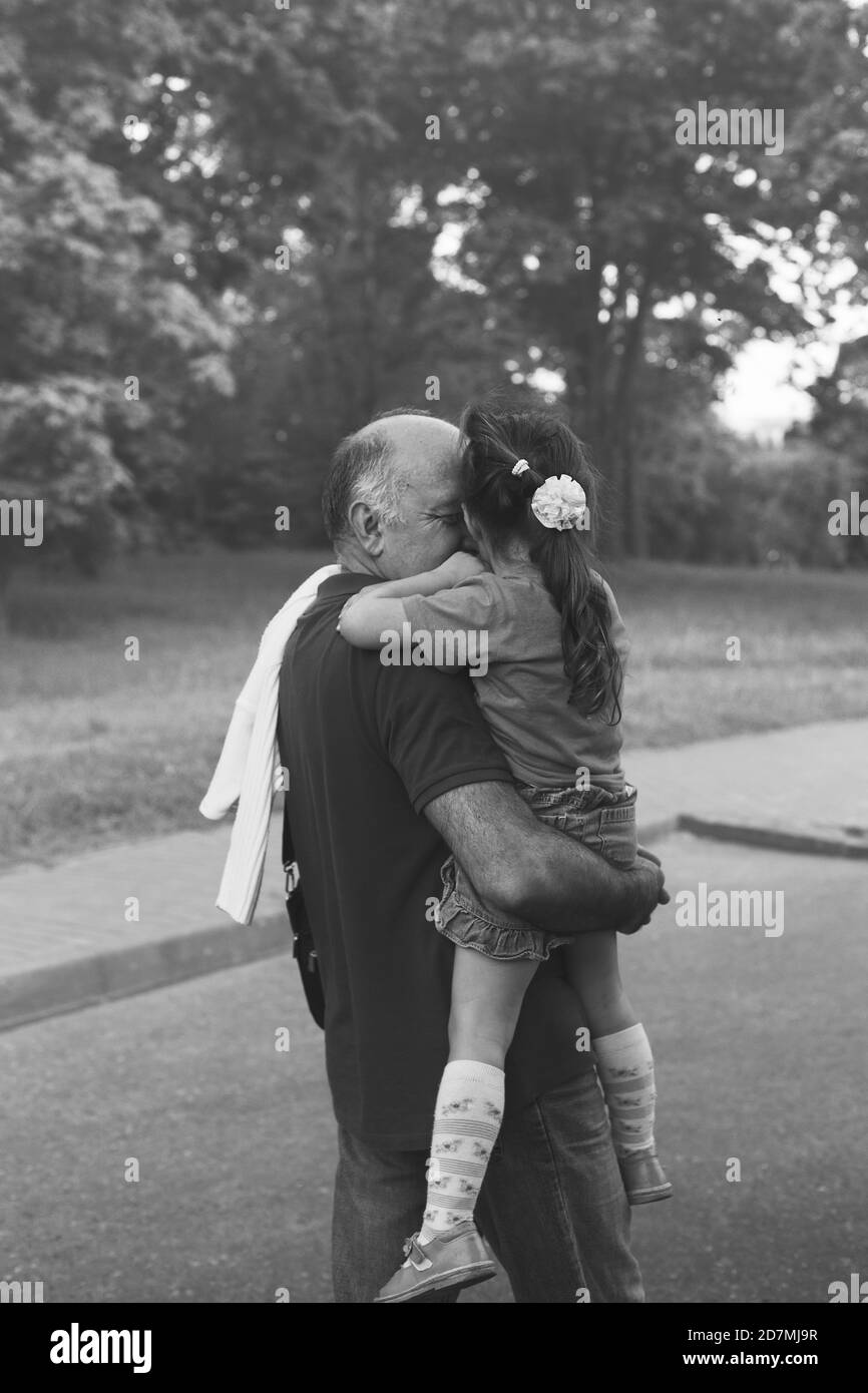 Black and white portrait of Happy granddad and grandaughter hugging at the park Stock Photo