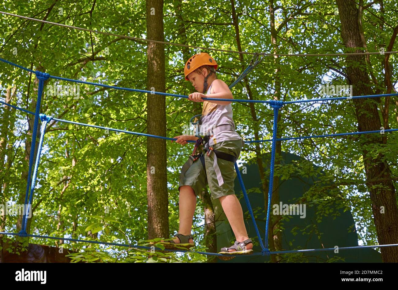 A boy with a helmet and insurance passes a high-altitude obstacle course. Workout Stock Photo