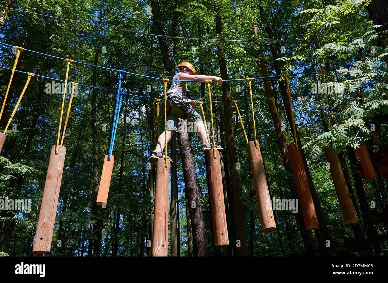 A boy with a helmet and insurance passes a high-altitude obstacle course. Workout Stock Photo