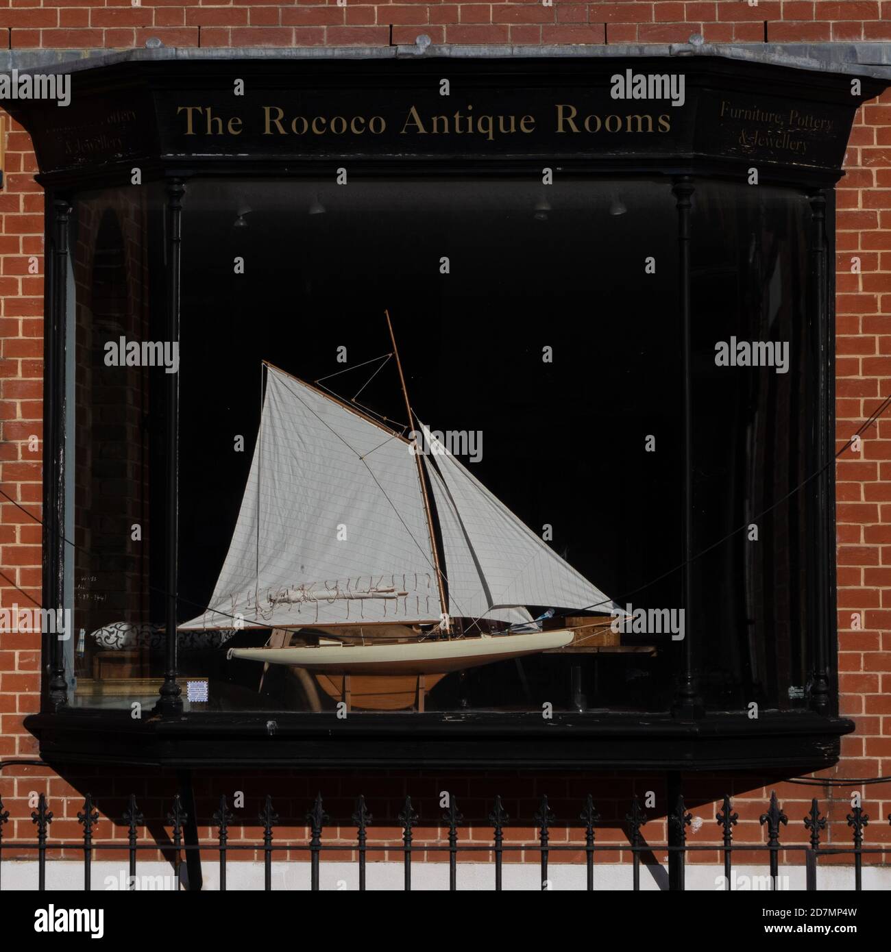 The sun picking out beautifully an antique model yacht in the window of Rococo Antique Rooms, Northam, Southampton, Hampshire, UK. Stock Photo