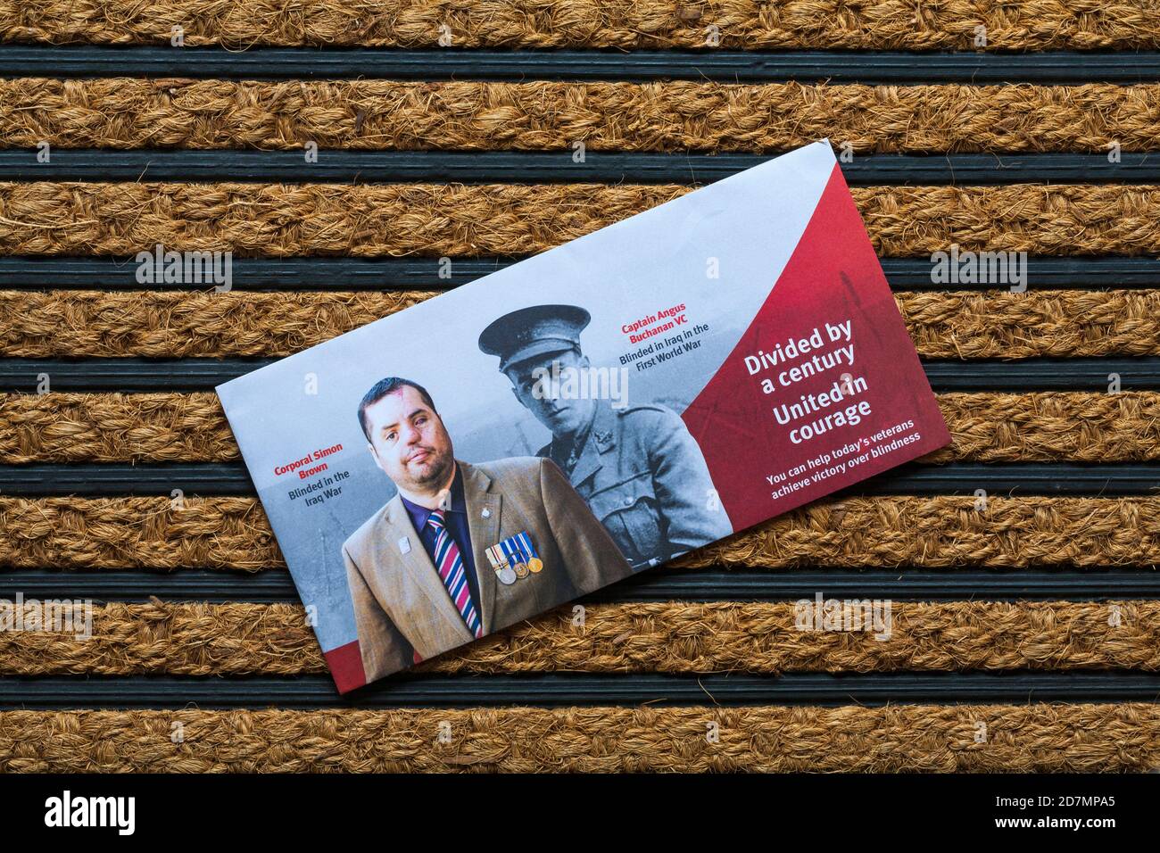 Post mail on doormat - divided by a century united in courage - you can help todays veterans achieve victory over blindness Stock Photo