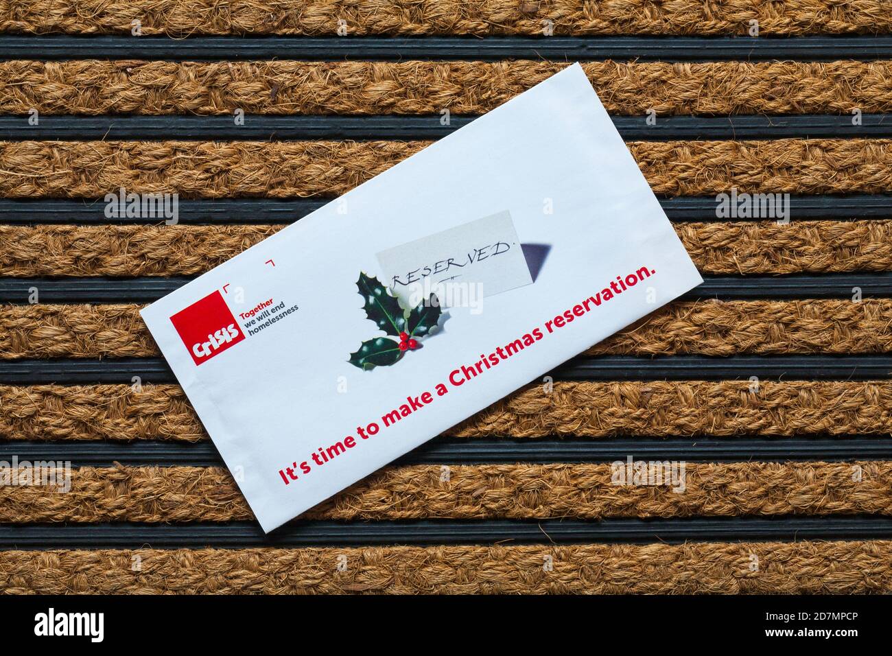 Post mail on doormat  - charity appeal, Crisis together we will end homelessness - it's time to make a Christmas reservation Stock Photo