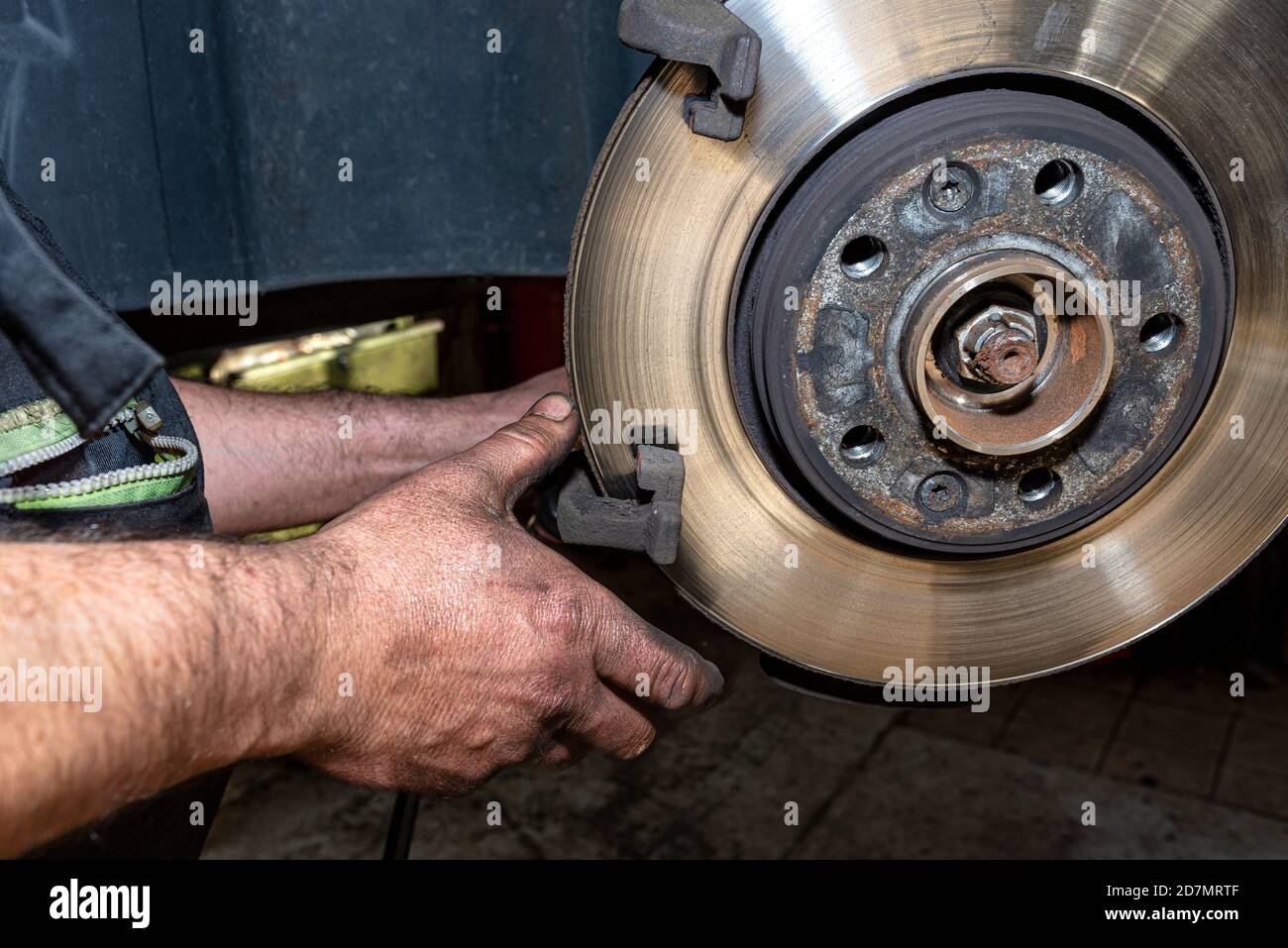 A car mechanic pulls a brake caliper in a car standing on a car jack in the  workshop Stock Photo - Alamy