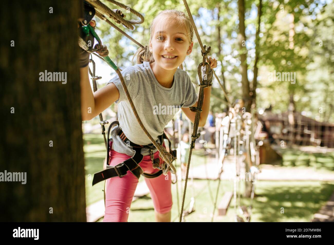 Smiling girl climbs in rope park, playground Stock Photo
