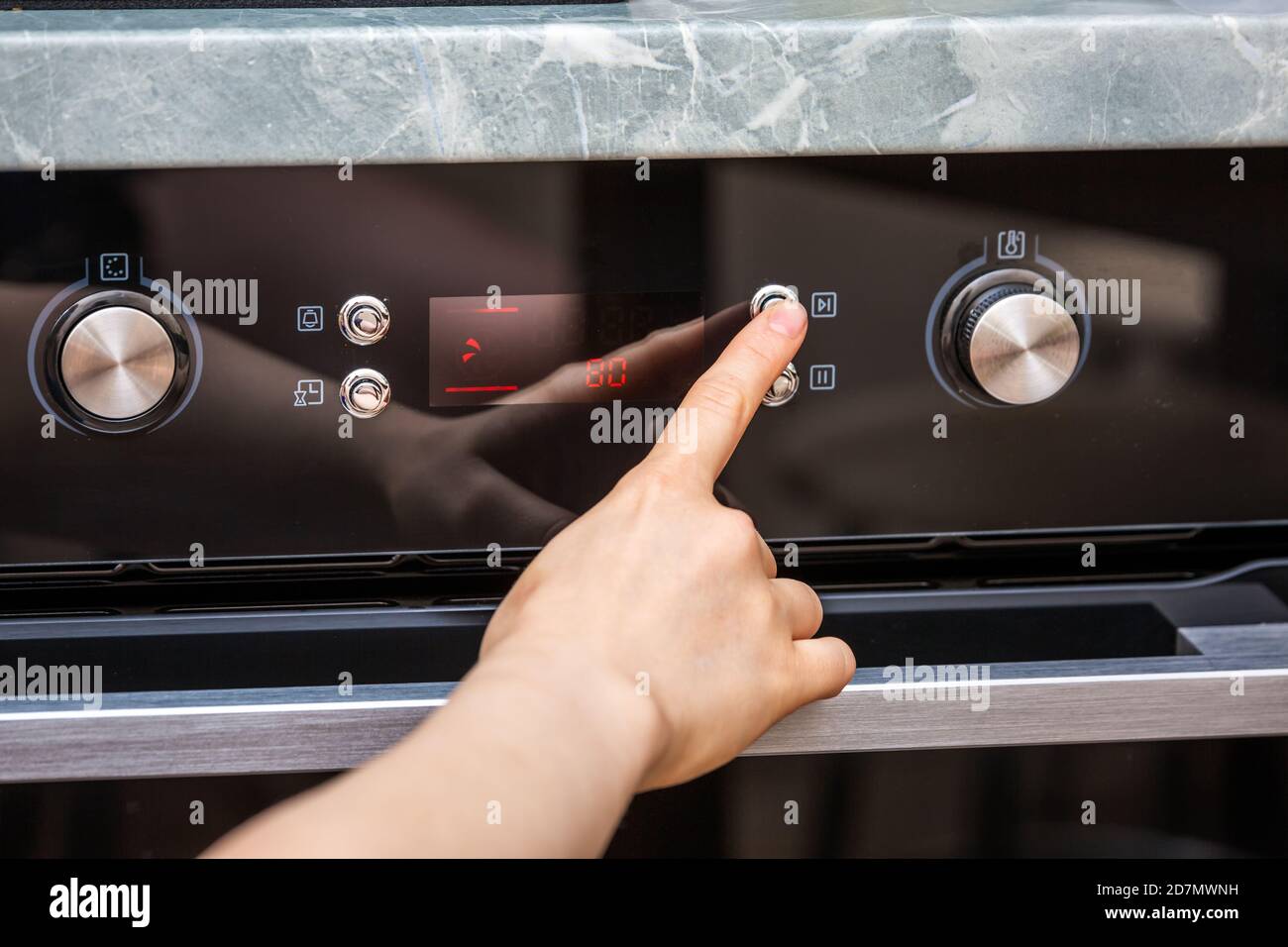 Female hand turning on the oven to make a cake at home. Closeup of the