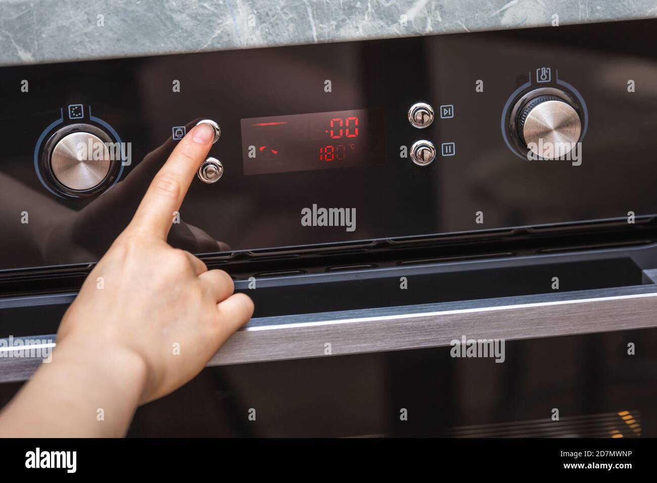Female hand turning on the oven to make a cake at home. Closeup of the
