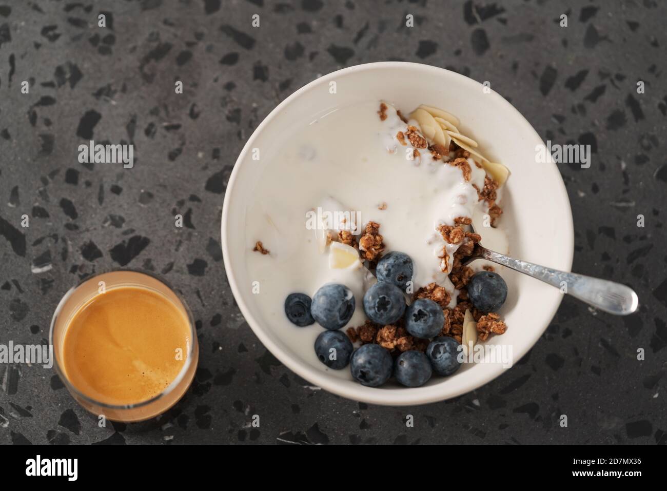 Healthy breakfast with whole grain granola and fresh blueberries in white bowl with coffee on concrete background, shallow focus Stock Photo