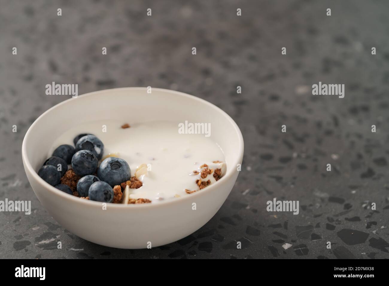 Healthy breakfast with whole grain granola and fresh blueberries in white bowl on concrete background, shallow focus Stock Photo