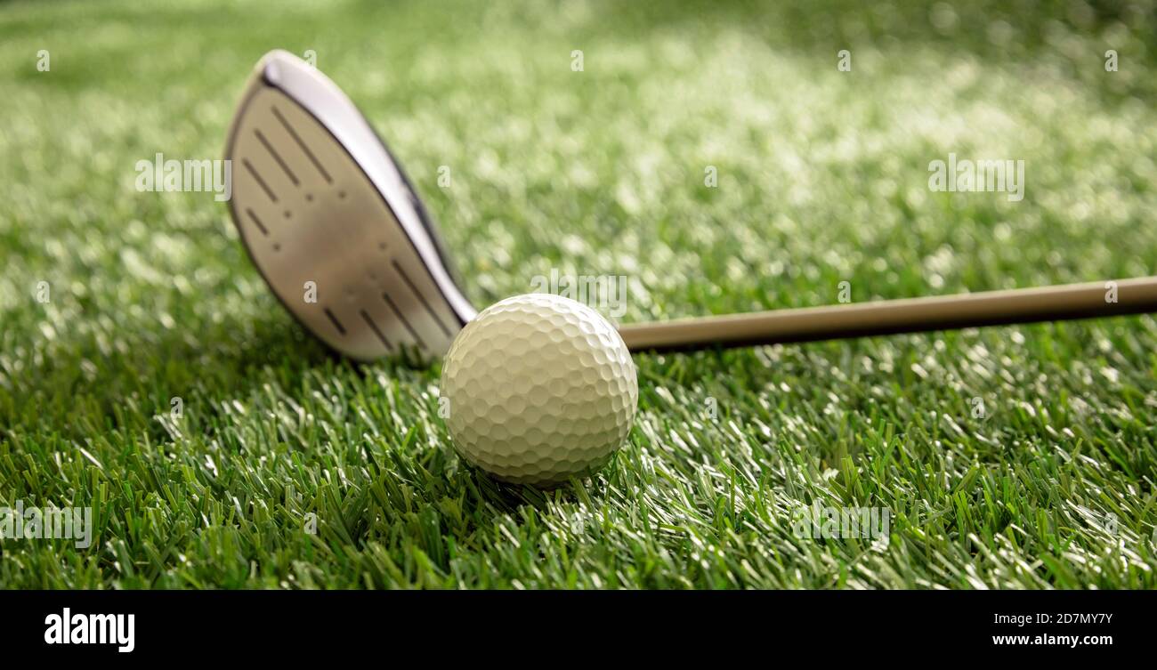 Golf ball and club on green course lawn, sunlight reflections, close up view. Golfing sport equipment concept. Stock Photo