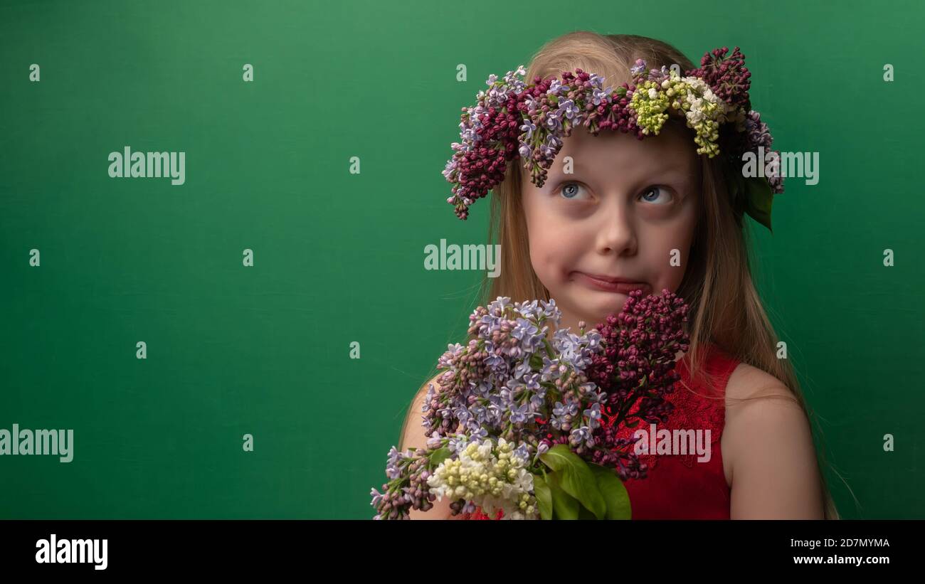 Auspicious youthful wonderful in a lilac wreath with white skin rejoices background green. Grimace Stock Photo
